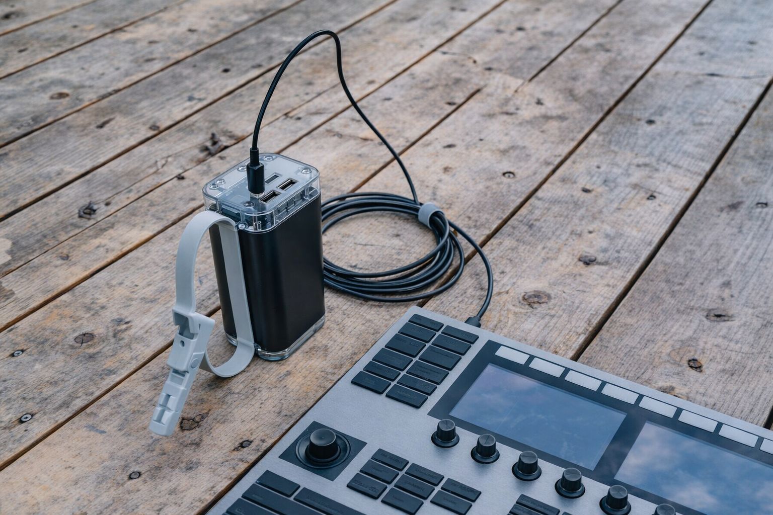 Portabel musikmaskin och kraftfull powerbank på ett trägolv.