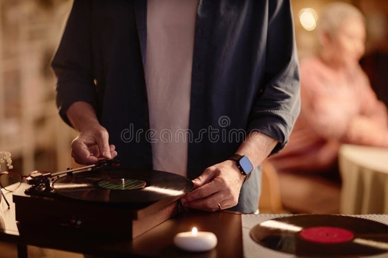 Person lägger en vinylskiva på en skivspelare vid middagsbordet