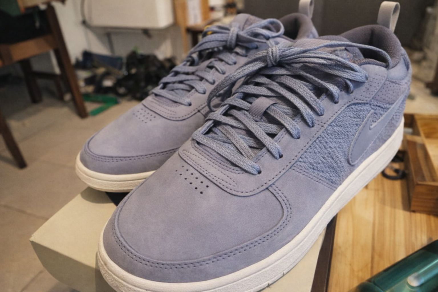 Närbild på blå sneakers i mocka som del av en modern vardagslook.